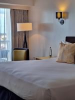 King bed by a balcony with a chair and a small table in Harbour Deluxe Balcony at Warwick Paradise Island Bahamas
