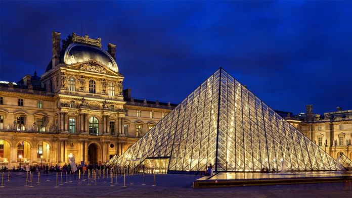 Exterior view of the Louvre Museum illuminated at night near Oceania Hotels