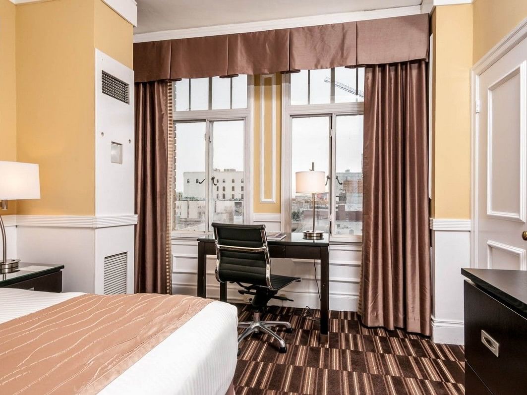 Hotel room with a bed, desk, and city view at Pickwick San Francisco.