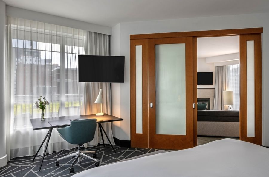 TV with work desk facing bed near doorway open to living area in Warwick Premier Suite at Warwick Le Crystal Montreal