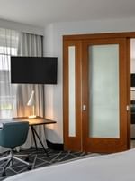 Hanging TV with work desk near bed and door open to living area in Warwick Premier Suite at Warwick Le Crystal Montreal