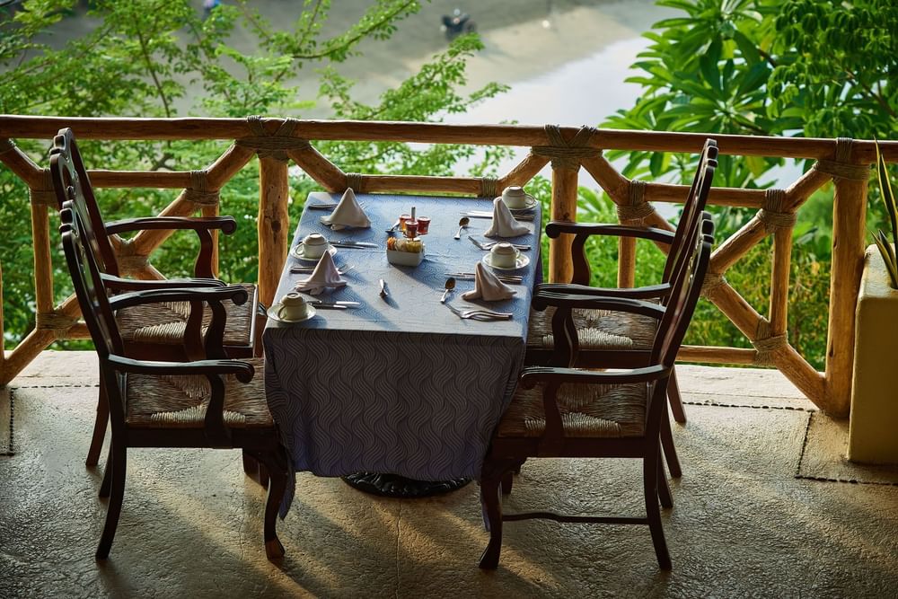 Intimate dinner table in Tierra Mia set with blue linens on a terrace near lush green trees at Quinta Real Acapulco