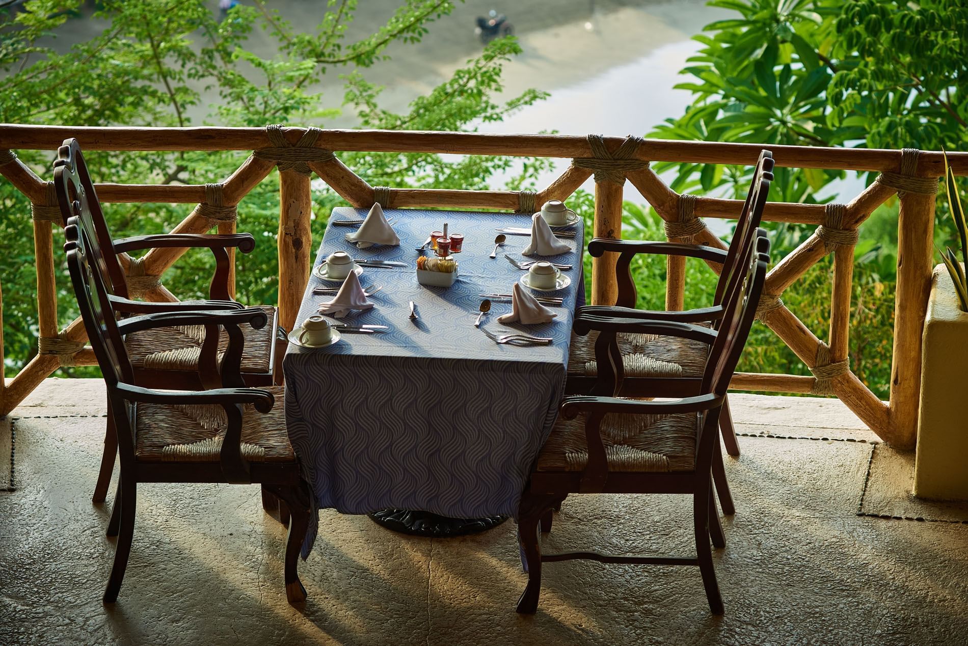 Intimate dinner table in Tierra Mia set with blue linens on a terrace near lush green trees at Quinta Real Acapulco