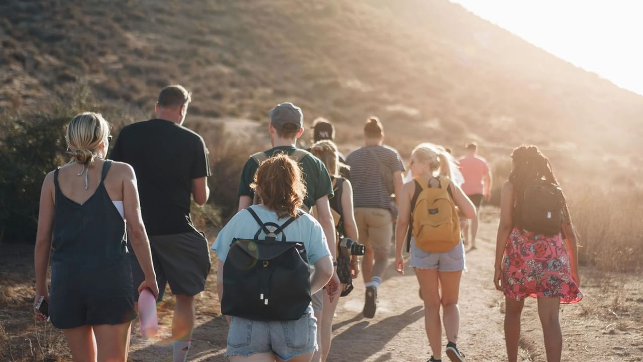 Group of people hiking on a sunny trail through scenic hills