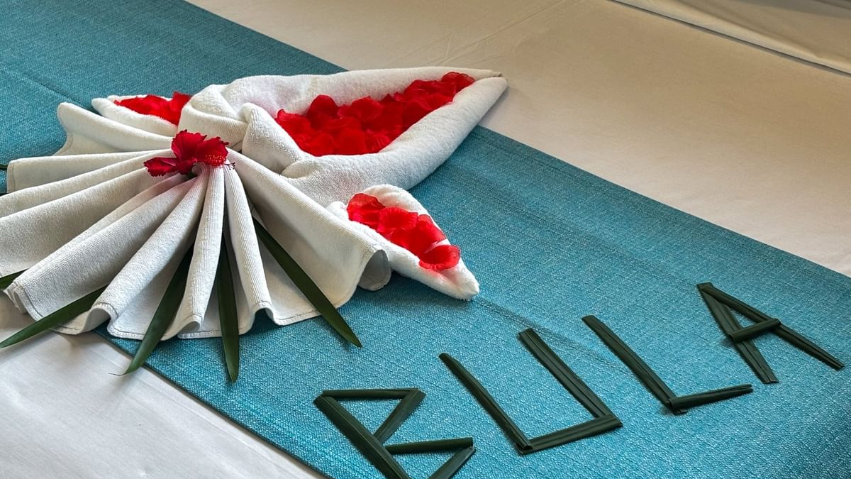Teal bed runner featuring leaf lettering and a white towel fan with red petals in Family Villa at TokaToka Resort Nadi Fiji