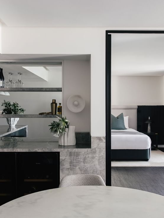 Elysium Two Bedroom Suite at Elysium Hotels bar with wine bottles and glasses beside the dark bedroom entrance