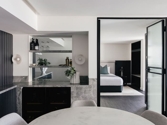 Elysium Two Bedroom Suite at Elysium Hotels bar with wine bottles and glasses beside the dark bedroom entrance