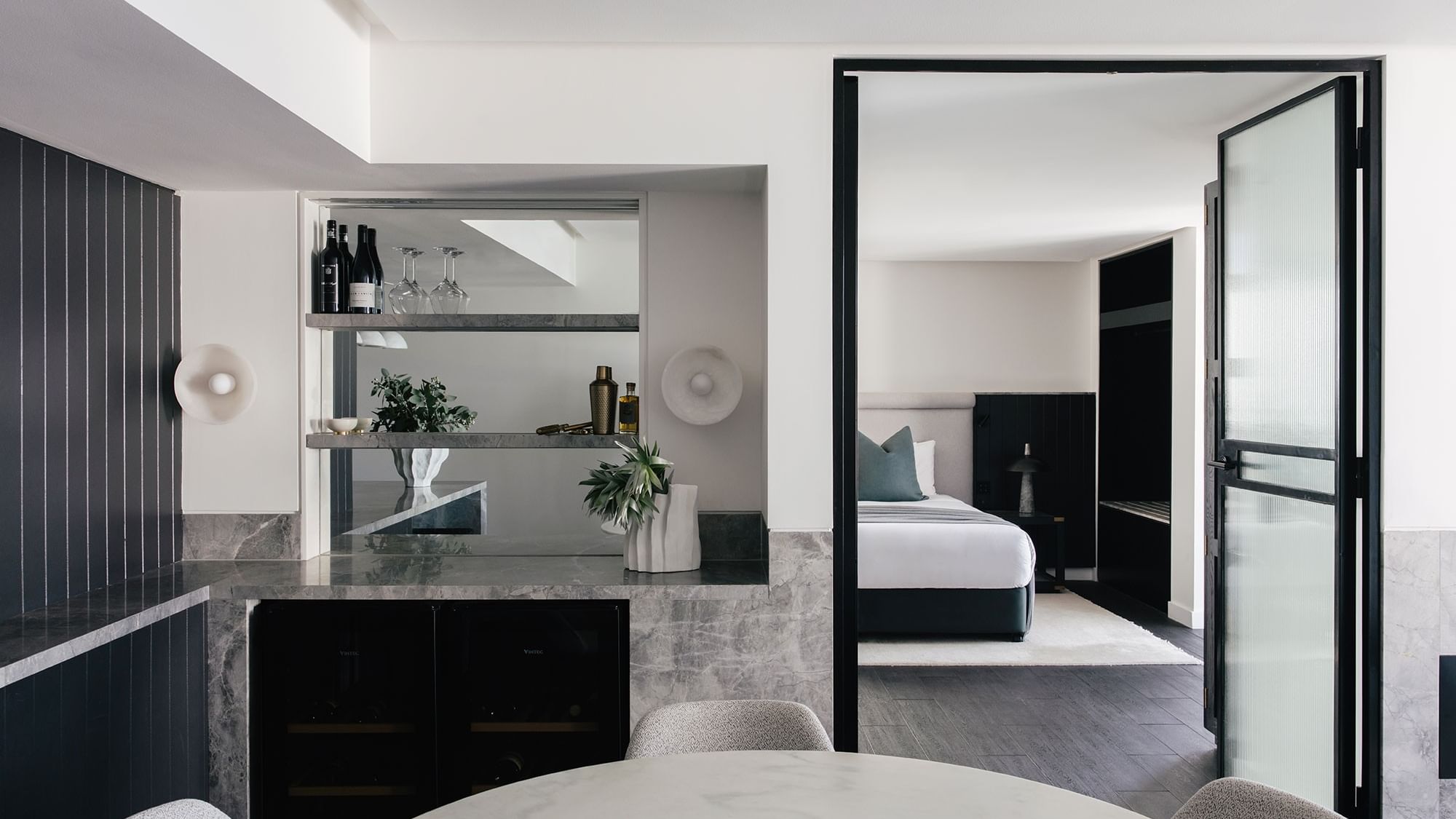Elysium Two Bedroom Suite at Elysium Hotels bar with wine bottles and glasses beside the dark bedroom entrance