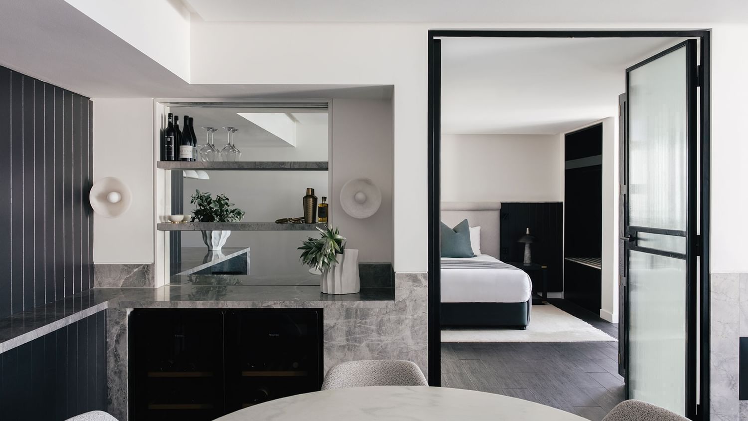 Elysium Two Bedroom Suite at Elysium Hotels bar with wine bottles and glasses beside the dark bedroom entrance