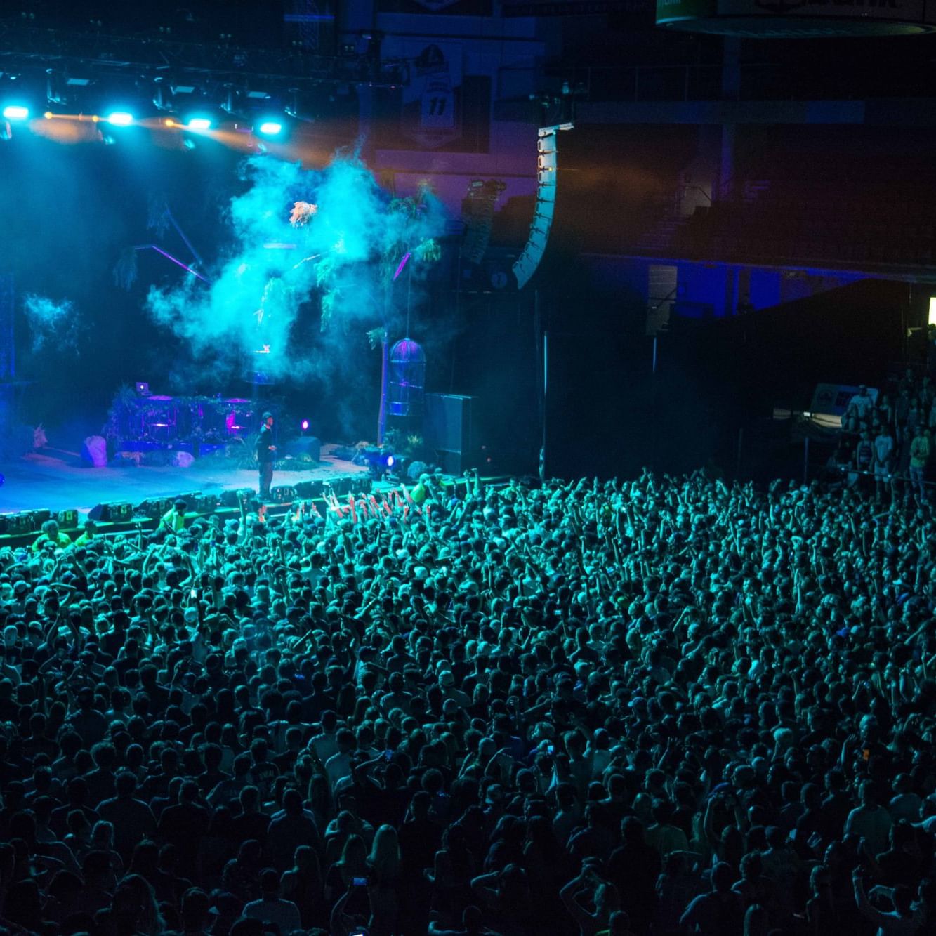 Crowded concert hall with blue stage lights and audience near Hotel 43