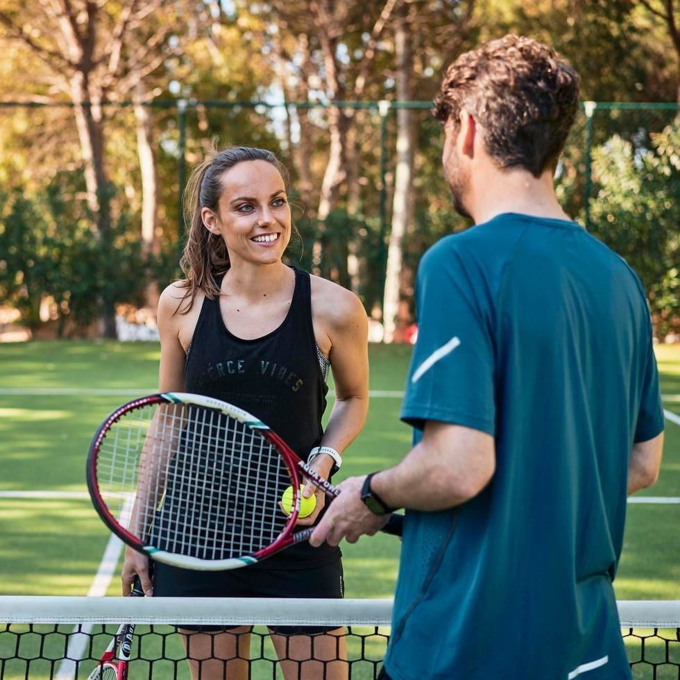 Two people with tennis racket and ball on a tennis court at Falkensteiner Residences Senia