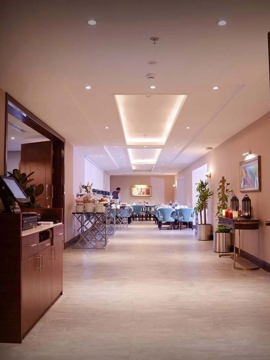 Al Multaqa Restaurant featuring light blue chairs by a buffet station under a recessed ceiling at Warwick Al Khobar