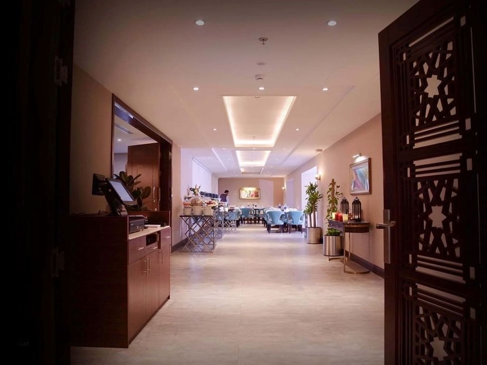 Al Multaqa Restaurant featuring light blue chairs by a buffet station under a recessed ceiling at Warwick Al Khobar