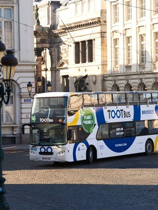 Double-decker bus with Planet Friendly branding and Brussels text driving on city street.