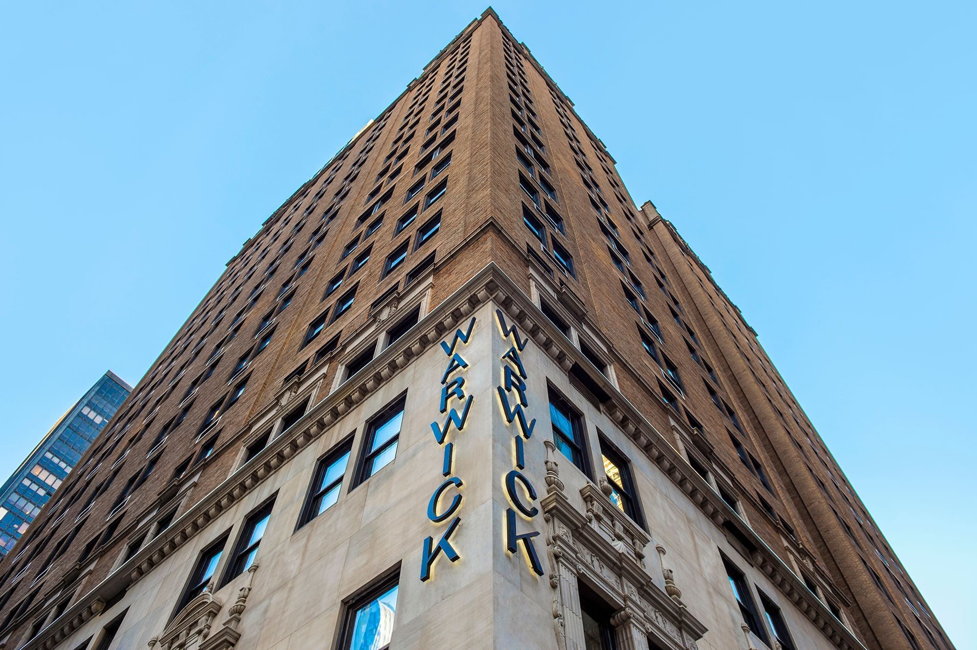 Tall Warwick building with blue letters and many windows under blue sky at Warwick New York