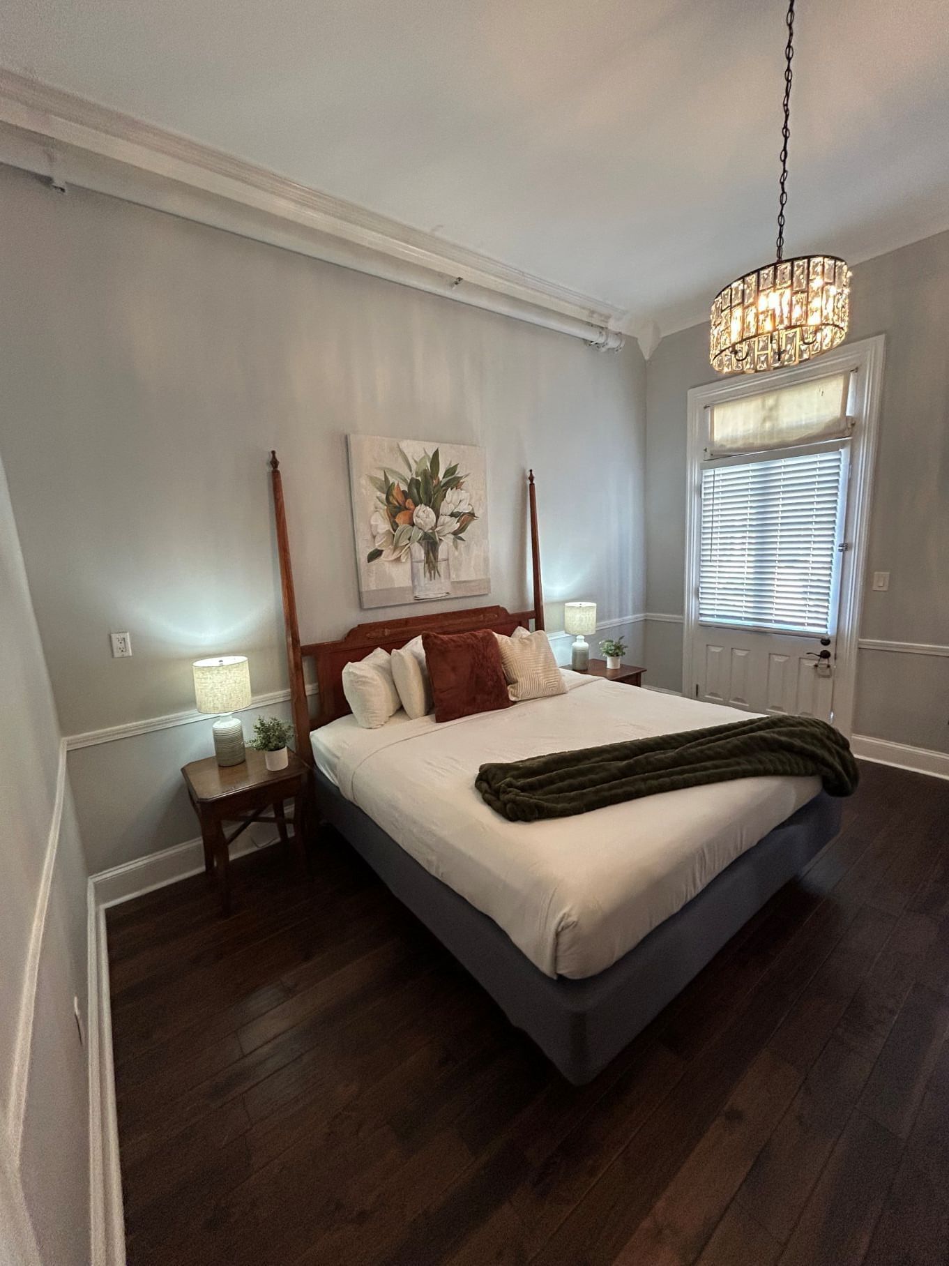  Elegant bedroom with one full bed, chandelier, and window at Hotel St. Pierre in New Orleans.