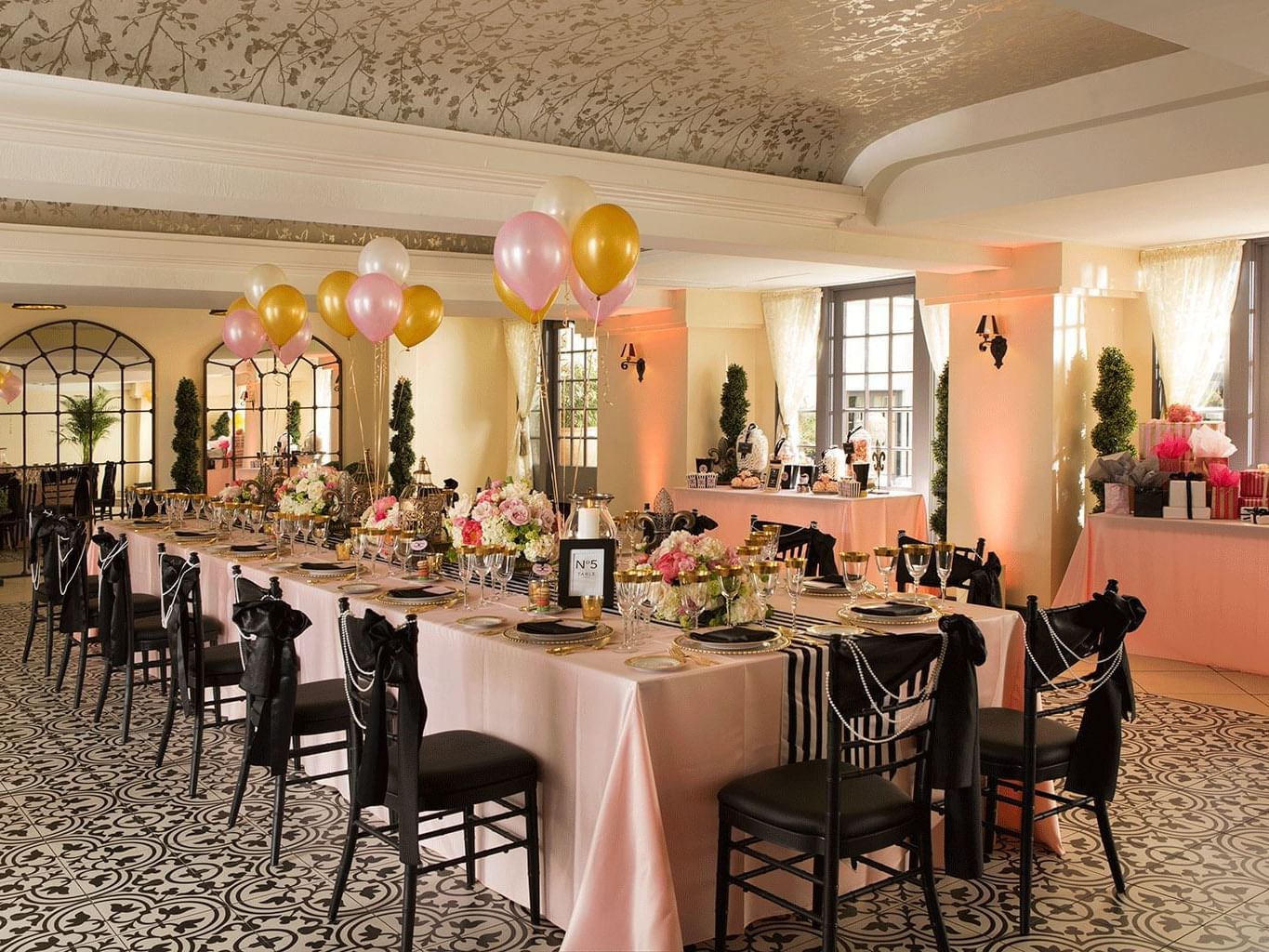 ballroom with large table with pink tablecloth and black chairs