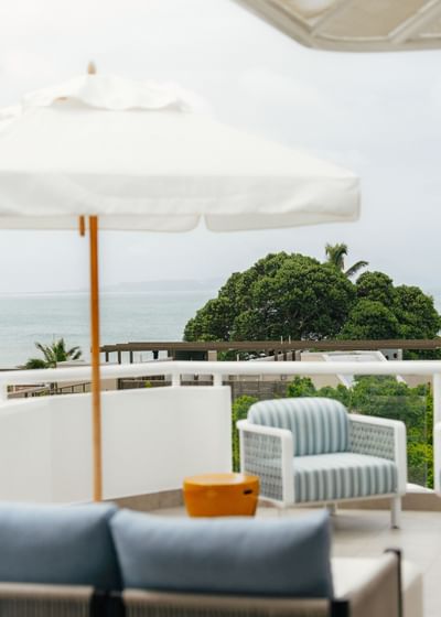 Elysium Hotels balcony with a striped armchair by a table overlooking sea and trees, best 5-star hotels in New South Wales