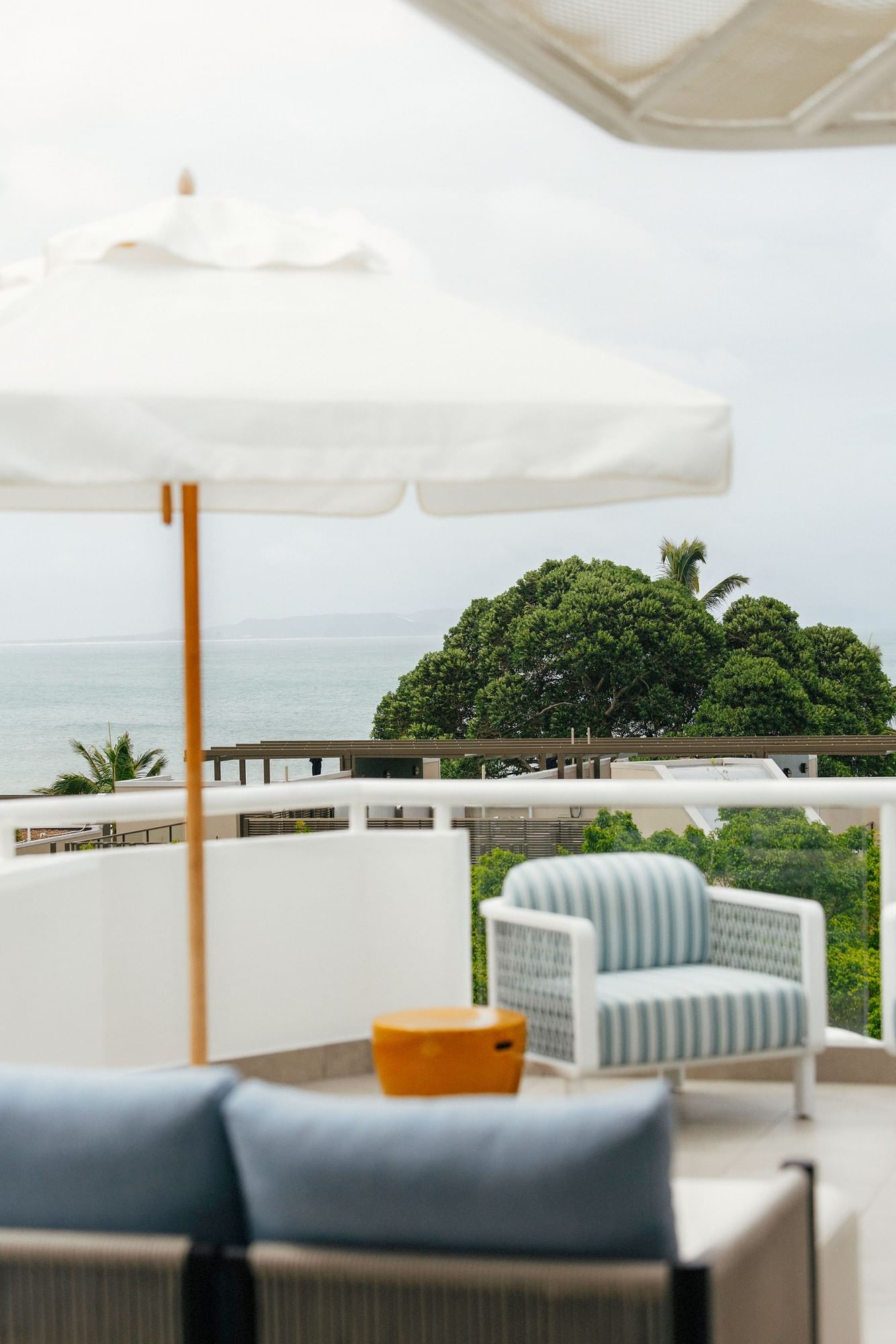 Elysium Hotels balcony with a striped armchair by a table overlooking sea and trees, best 5-star hotels in New South Wales