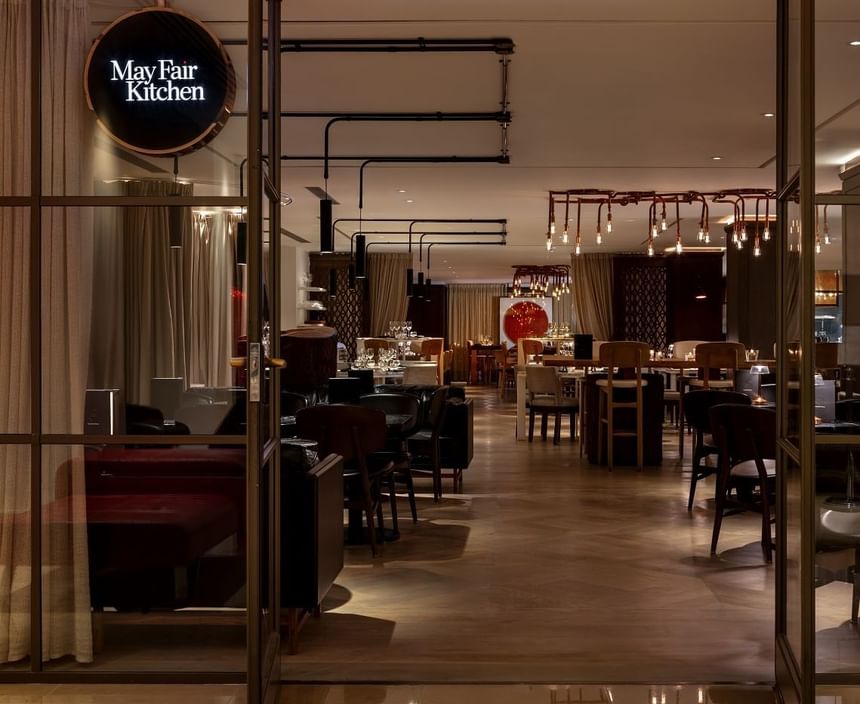 Elegant interior of May Fair Kitchen featuring an inviting dining area with varied seating and warm ambient lighting