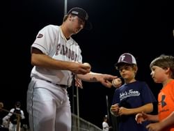 A baseball player signing autographs near Falmouth Tides