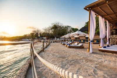 Sunbeds under cabanas arranged outdoors on seashore by the sea at Hotel Isla Del Encanto