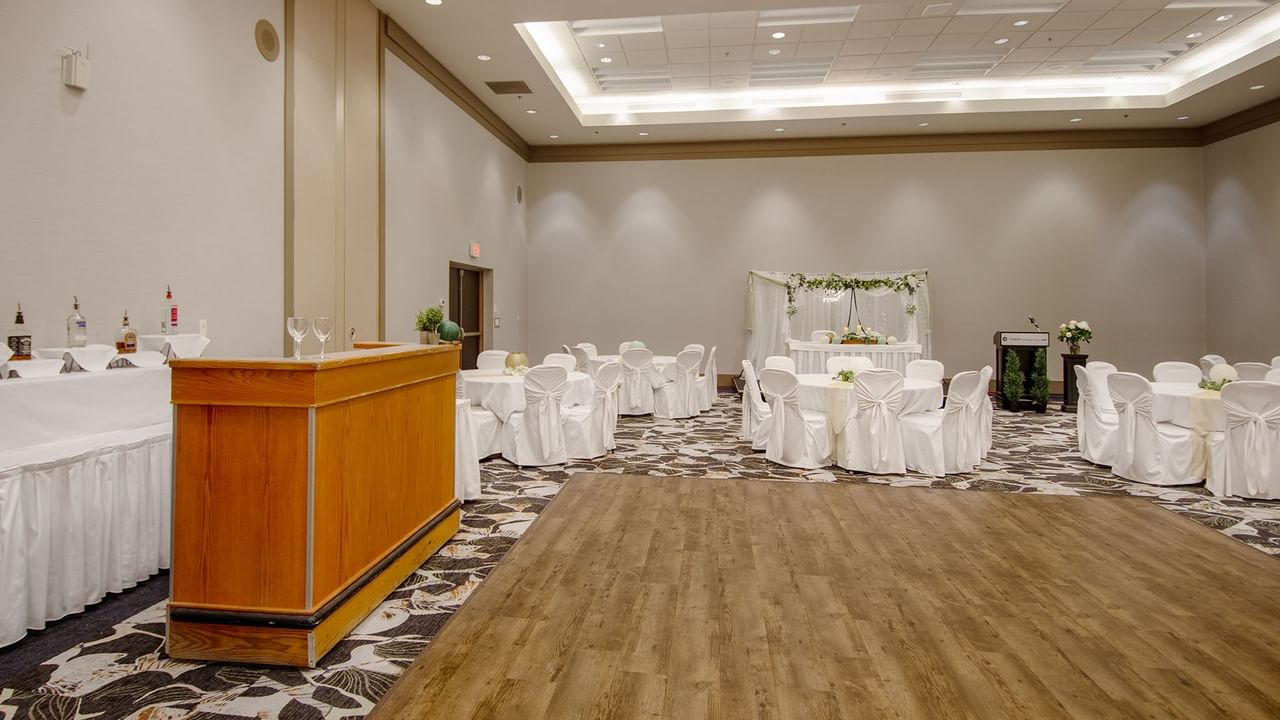 Banquet hall with tables, chairs, and a podium, arranged for a wedding.