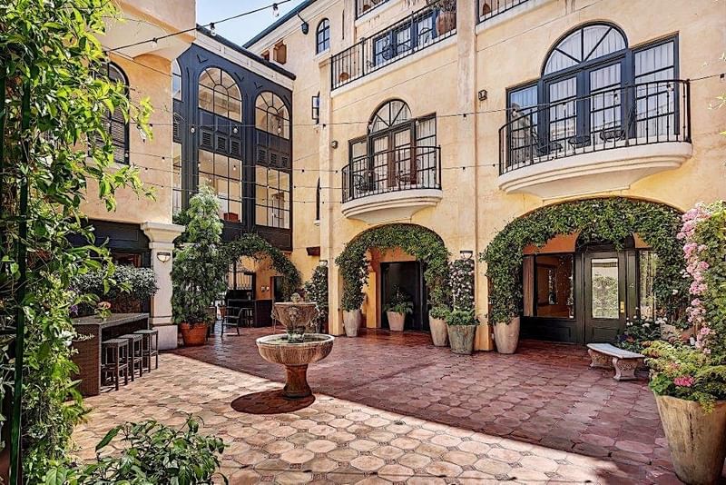 Courtyard with charming balconies and central fountain surrounded by lush greenery at El Prado Hotel