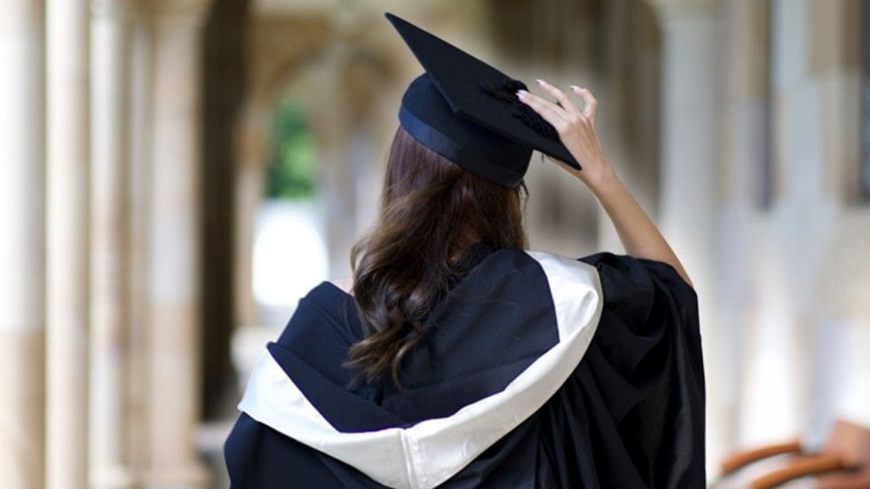 Stock image of a student in graduation clothing on Australian university campus grounds.