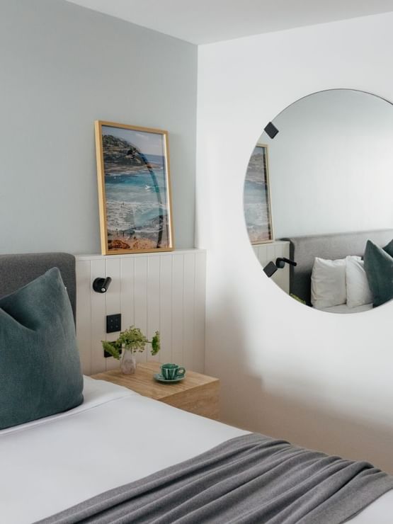 Ocean View Twin – Elysium Floor at Elysium Hotels with teacup and saucer by a vase on a nightstand under a round wall mirror