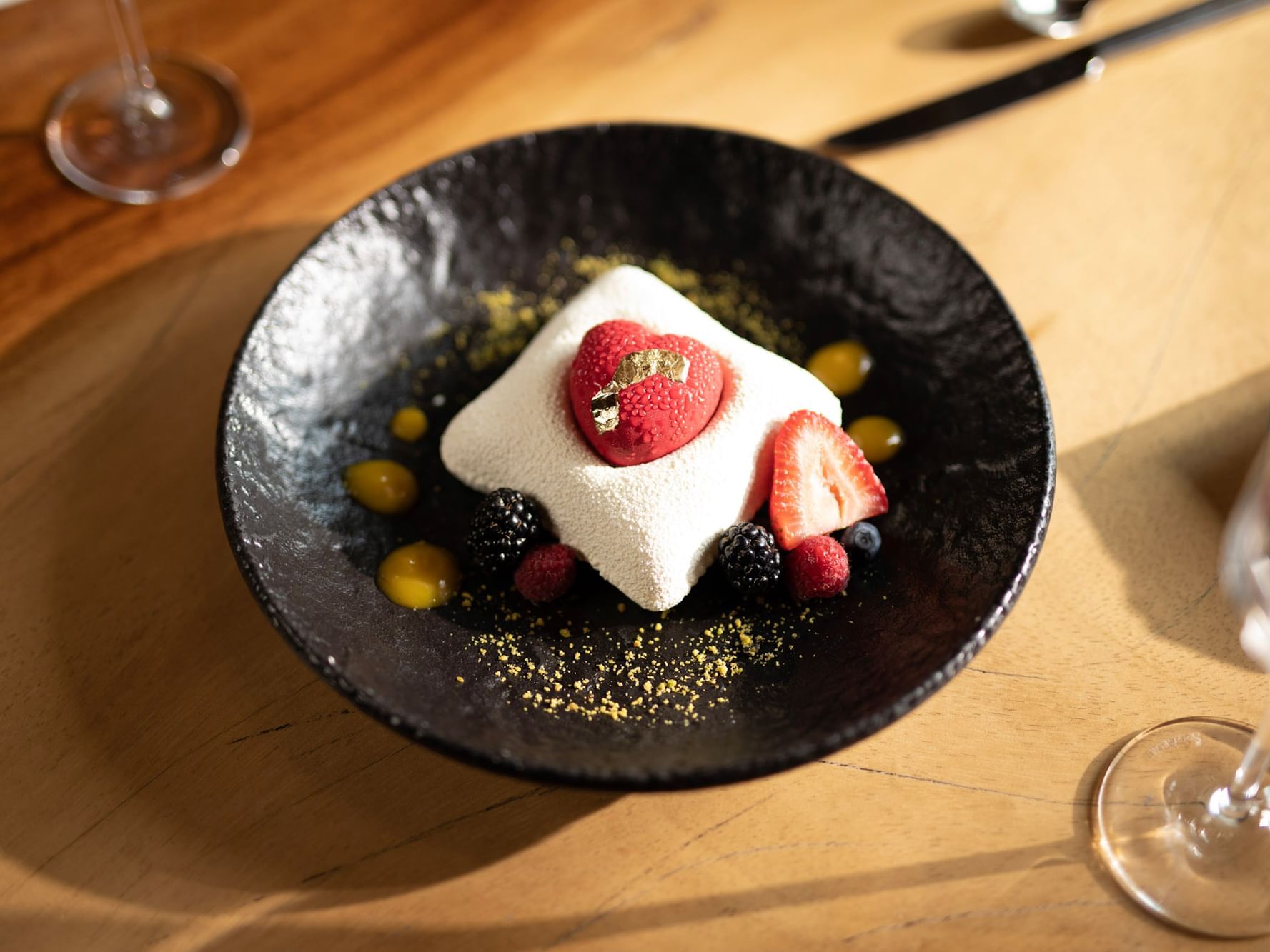 Dessert featuring a heart-shaped mousse, and berries on a dark textured plate at Live Aqua San Miguel de Allende