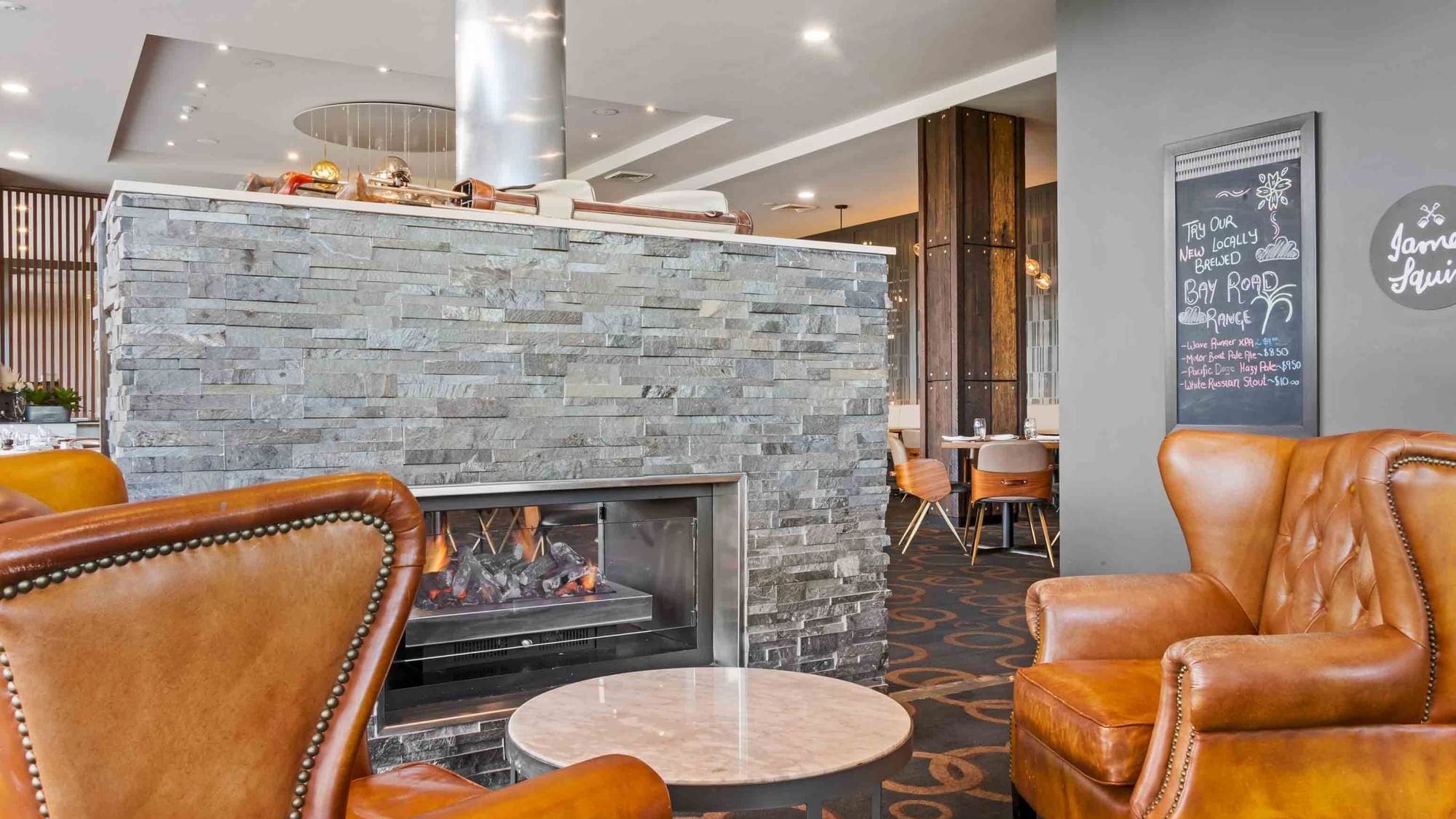 Wine Bar with a stone fireplace, leather chairs, and a chalkboard menu at Mercure Kooindah Waters