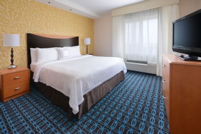 room with bed, nightstand and television on dress