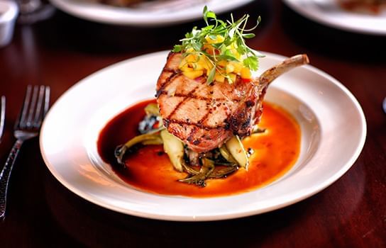 Grilled pork chop with garnish on a plate served in a restaurant near Lake Buena Vista Resort Village & Spa