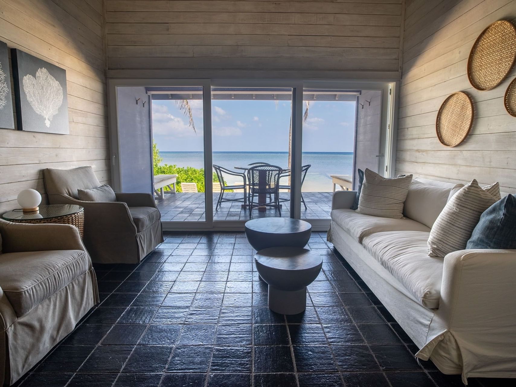 Living area by sliding doors featuring outdoor seating in Two Bedroom Oceanfront Villa at Barefoot Cay Resort & Marina