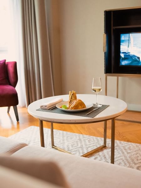 Cozy setting with a white round table featuring a sandwich and a glass of wine in a room at Warwick Reine Astrid - Lyon