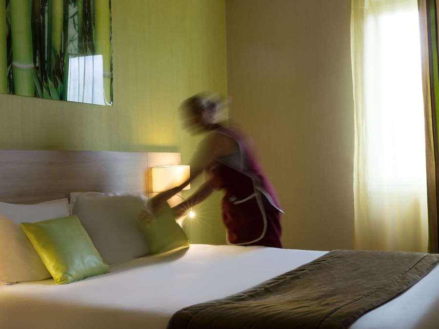 A Woman preparing a Standard Double bed at Hotel des Lys