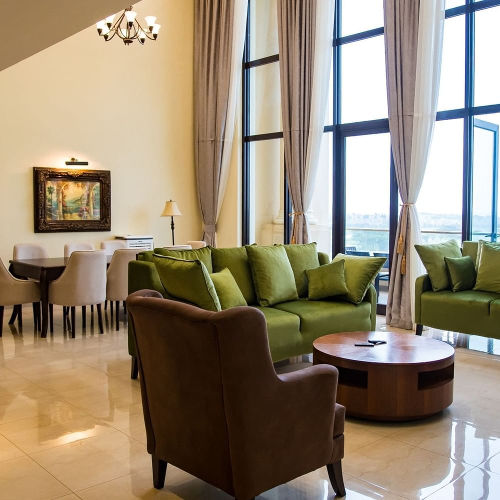 Elegant living room with green couches, wooden table, and dining area at Lake Victoria Serena Golf Resort & Spa in Kampala.