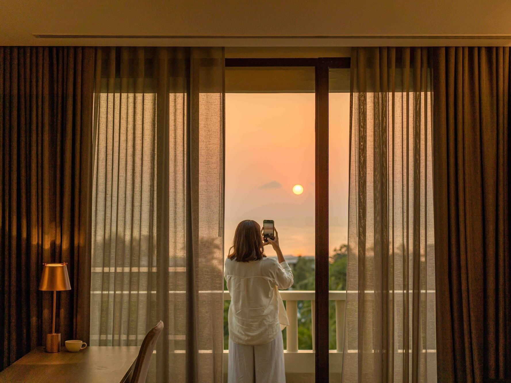 A woman is taking a photo of stunning sunset view from her own balcony in Paradox Seaview