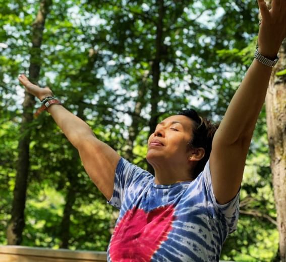 Woman with stretched hands and closed eyes near Honor’s Haven Retreat