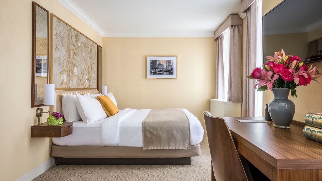 Executive King with a striped bed, floral art, and a wooden desk at Warwick Allerton Chicago