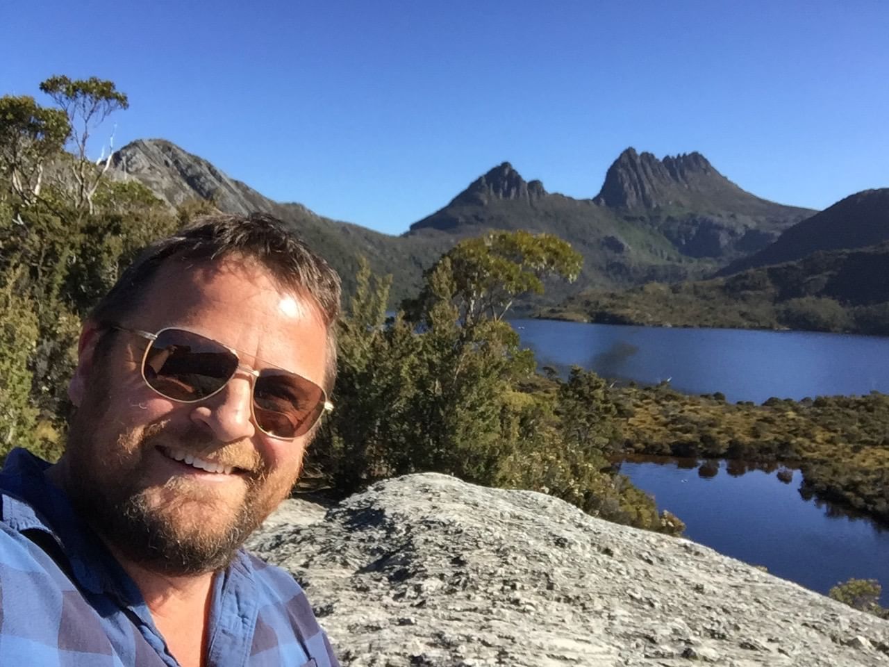 A man taking a selfie by dove lake near Cradle Mountain Hotel