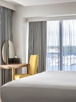 Yellow chair by a wooden desk and a round mirror in One Bedroom Harbourfront Suite at Warwick Paradise Island Bahamas