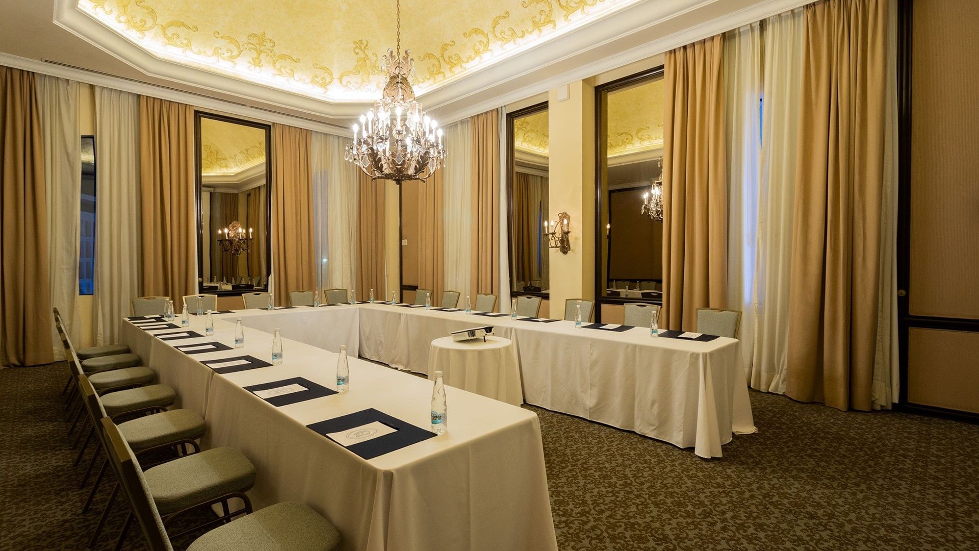 Salon Torre Ejecutiva with white linens, gold accents, and a crystal chandelier at Quinta Real Monterrey 