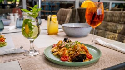 Seafood pasta with mussels and tomatoes beside a fresh mojito cocktail at Sand Street Bistro in Sugar Cane Club Hotel & Spa