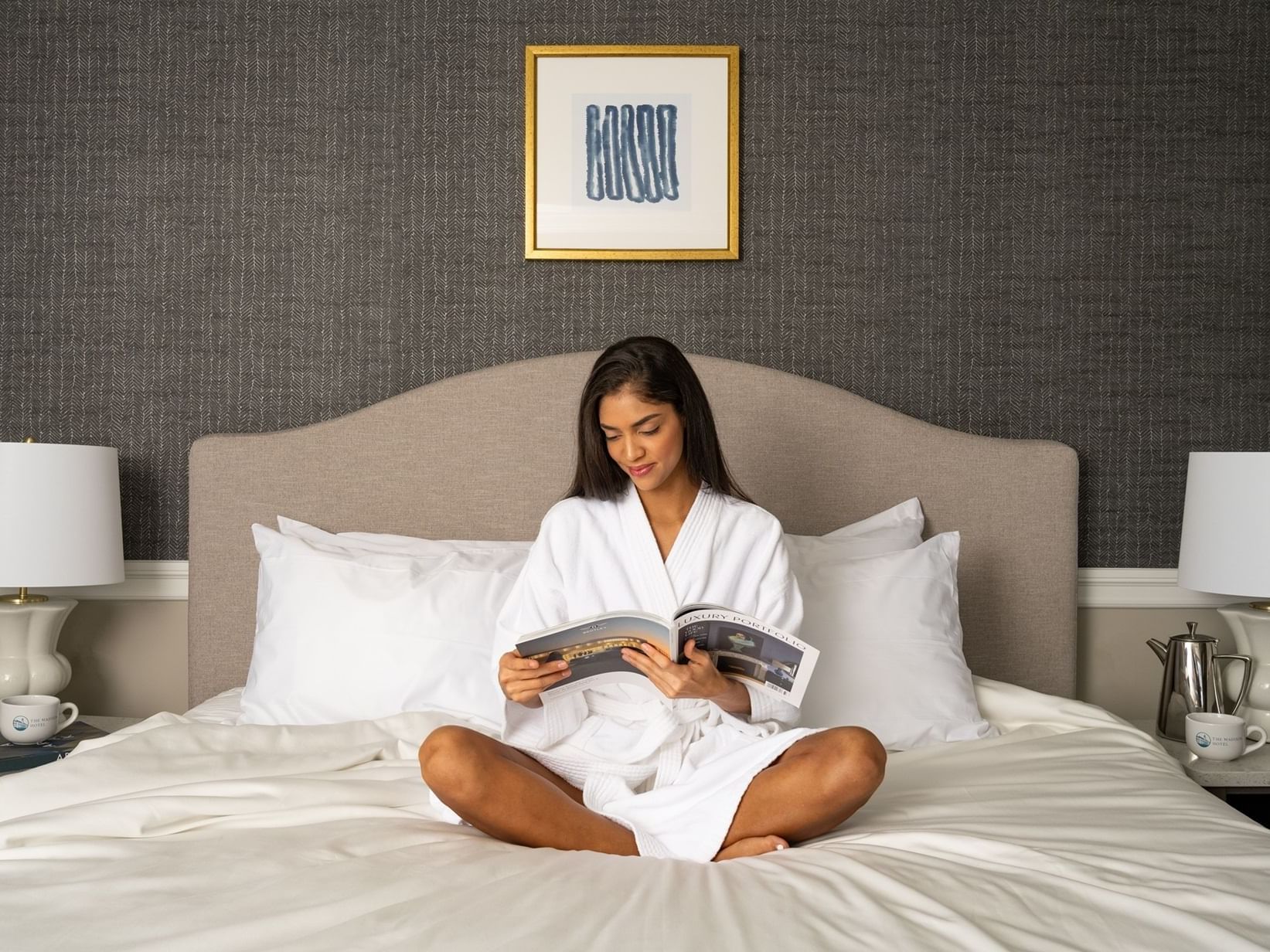 A woman reading a magazine on the bed at The Madison Hotel