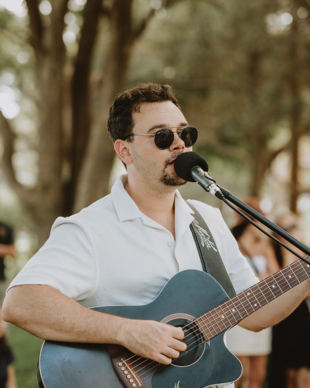 Ben Woodham playing an acoustic guitar outdoors at Mercure Kooindah Waters