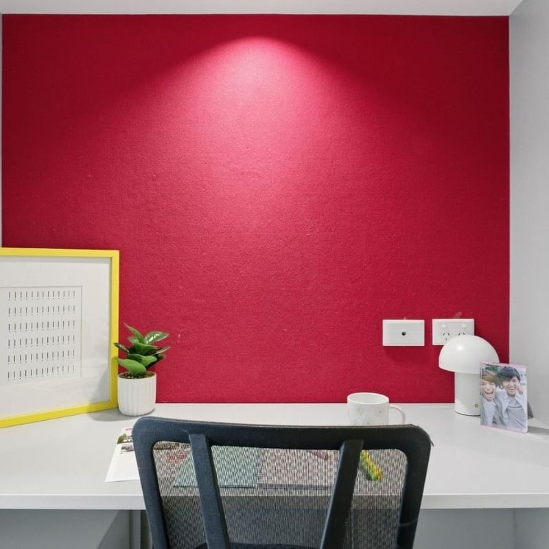 Small desk with chair, cup, picture, and plant at UniLodge Auckland City.