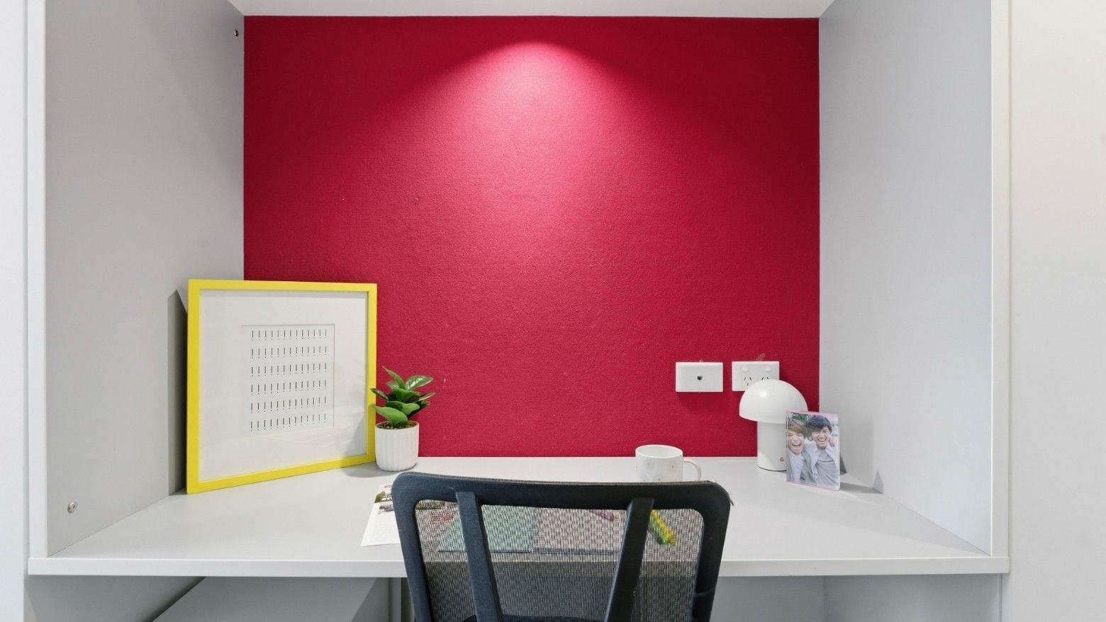 Desk with chair, coffee cup, picture frame, and potted plant at UniLodge Auckland City.