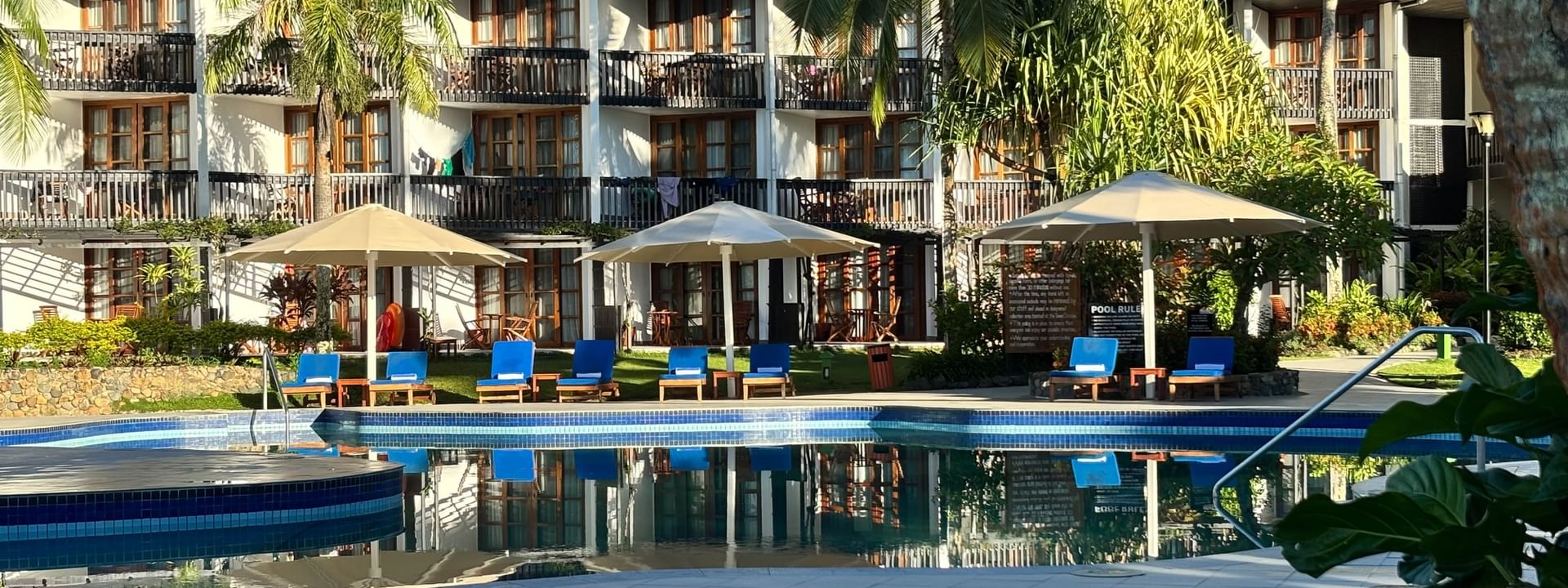Swimming pool with lounge chairs under umbrellas at Warwick Fiji Resort and Spa in Korolevu